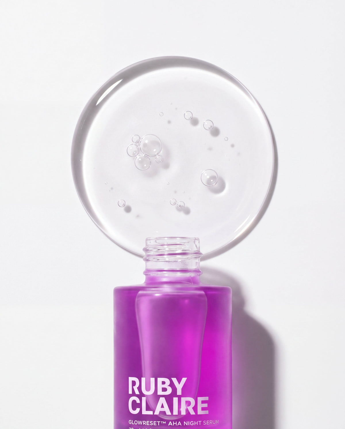 Ruby Claire GlowReset serum texture disc above the open bottle