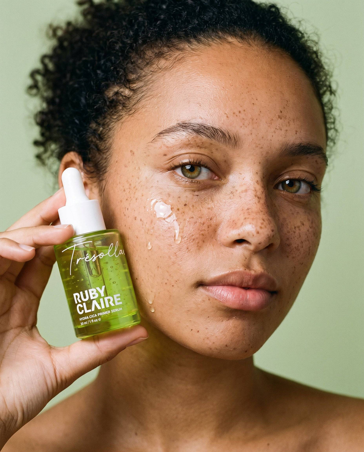 Model holding Ruby Claire Hydra Cica Primer Serum beside her cheek