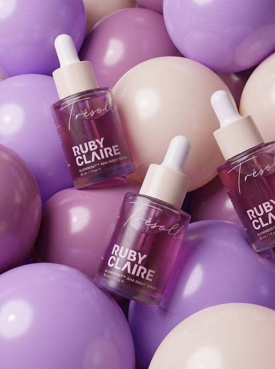 Ruby Claire GlowReset AHA Night Serum bottles on a bed of lilac balloons